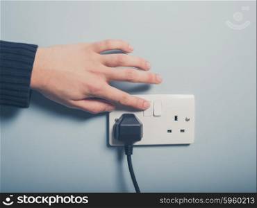 A male hand is pushing a switch on a wall socket
