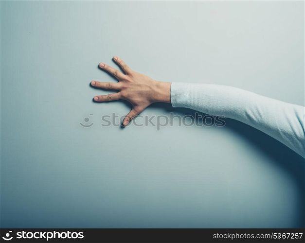 A male hand is touching a blue wall