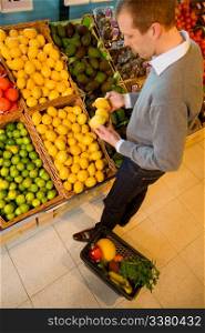 A male in a grocery store buying lemons - sharp focus on lemons