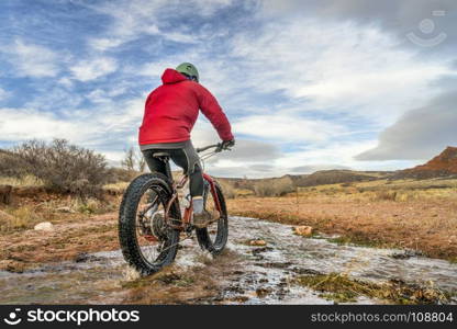 a male riding a fat bike across a stream in Red Mountain Open Space, Colorado , late fall scenery