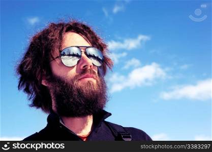 A male with a full beard and retro sunglasses standing in a winter landscape - cross processed