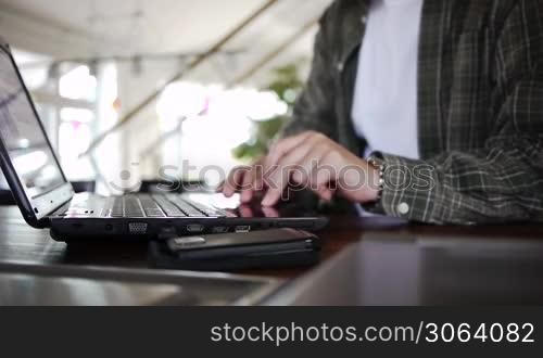 a male works on a notebook on a desk or table, ein Mann arbeitet an seinem Notebook auf einem Tisch