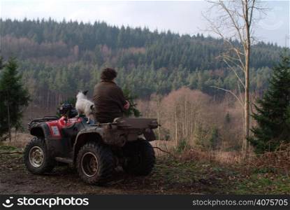 A man and a terrier on a quad bike