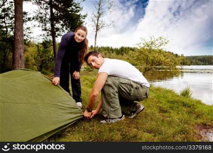 A man and woman camping - setting up a tent