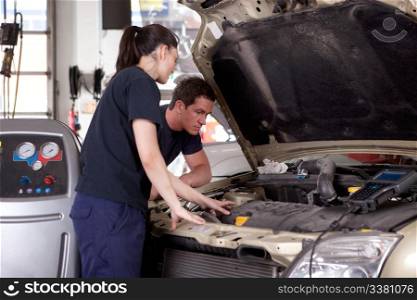 A man and woman mechanic working on a car in a auto repair shop