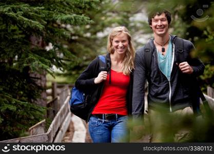 A man and woman on a hike in the forest, smiling at the camera
