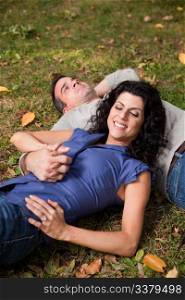 A man and woman relaxing in the park laying in the grass and dreaming - focus on the woman