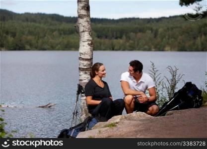A man and woman taking a break while on a camping hike