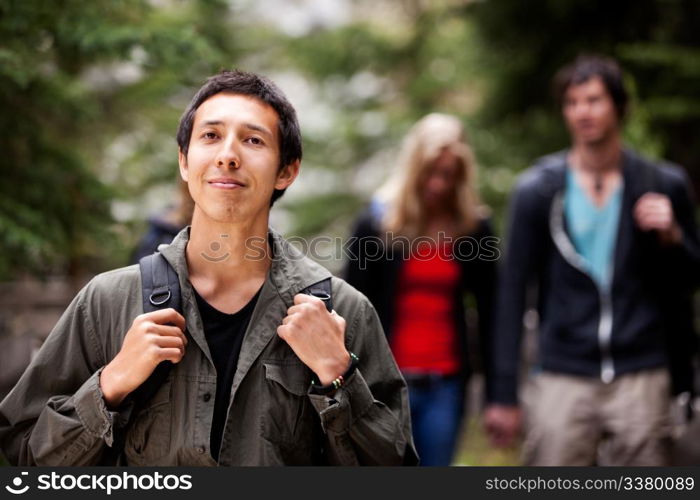 A man backpack camping in the forest with a group of friends in the background