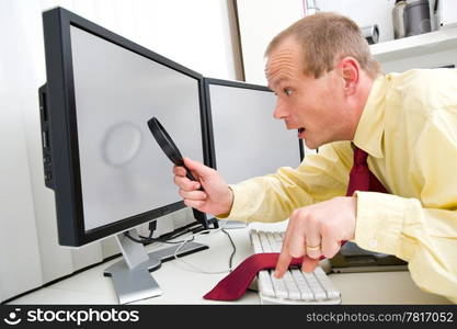 A man being surprized while scruitining a computer monitor with a magnifying glass, his left index finger hovering above the Escape key