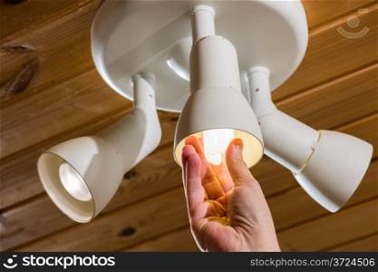 A man changes an electric light bulb, energy efficiency