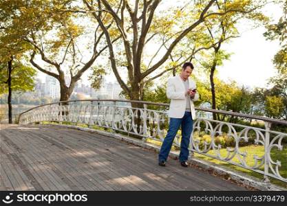 A man checking his cell phone in a park