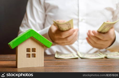 A man counts money on the background of the figures of the house. Calculation of property tax, payment of utilities. Counting repairing costs or buying a home. Financial difficulties, micromanagement