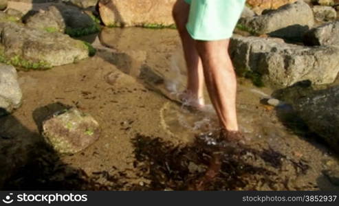 A man crossing through the Mediterranean seashore.Walking along the beach between the rocks.Morning walk along the beach.