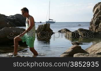 A man crossing through the seashore.Walking along the beach between the rocks.Morning walk along a Mediterranean beach.