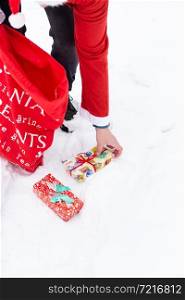 A man dressed as Santa Claus collects gifts in a snowy forest in the snow, colorful boxes with gifts. A man dressed as Santa Claus collects gifts in a snowy forest in the snow, colorful boxes with gifts.