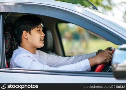 A man driving a car opens the window and smiles.