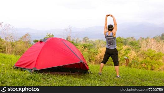 A man exercise and Athlete Warming Up in morning near tent on camping trip on the mountain