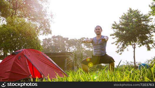 A man exercise and Athlete Warming Up in morning near tent on camping trip on the mountain