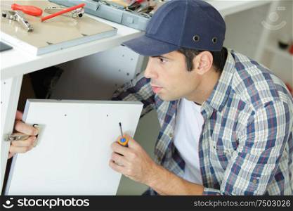 a man fixing a cupboard