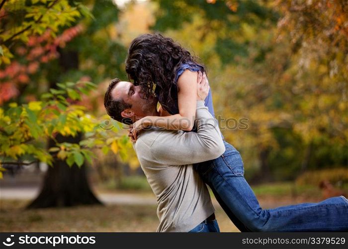 A man giving a woman a big hug in a park