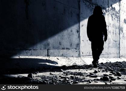 A man going out of an abandoned tunnel leaving a strong shadow behind. Man going to light.