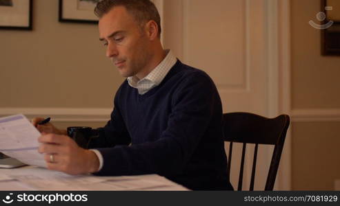 a man going over his bills on his dining room table