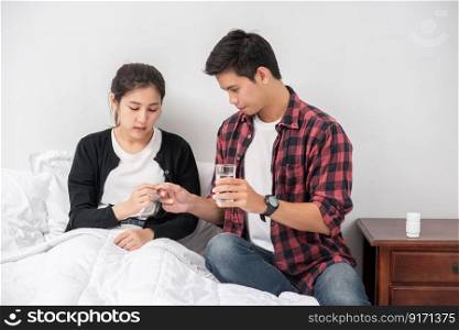 A man handed medicine to a sick woman in bed.
