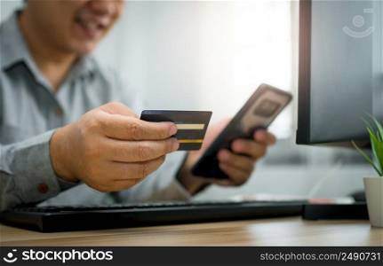 A Man holding credit card and using smartphone for payment online for purchase after order products via the internet. The concept of technology for e-commerce  electronic commerce 