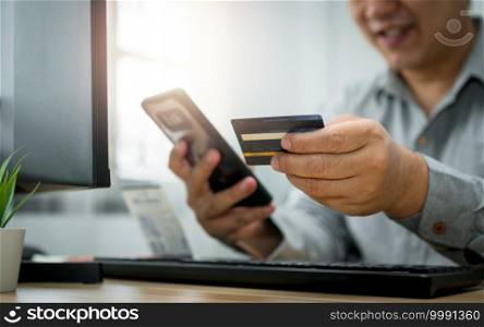 A Man holding credit card and using smartphone for payment online for purchase after order products via the internet. The concept of technology for e-commerce  electronic commerce 