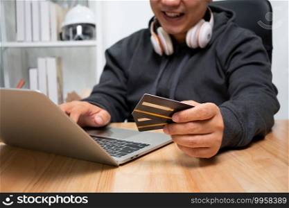 A Man holding dummy credit card and using laptop for payment online for purchase after order products via the internet. The concept of technology for e-commerce  electronic commerce 