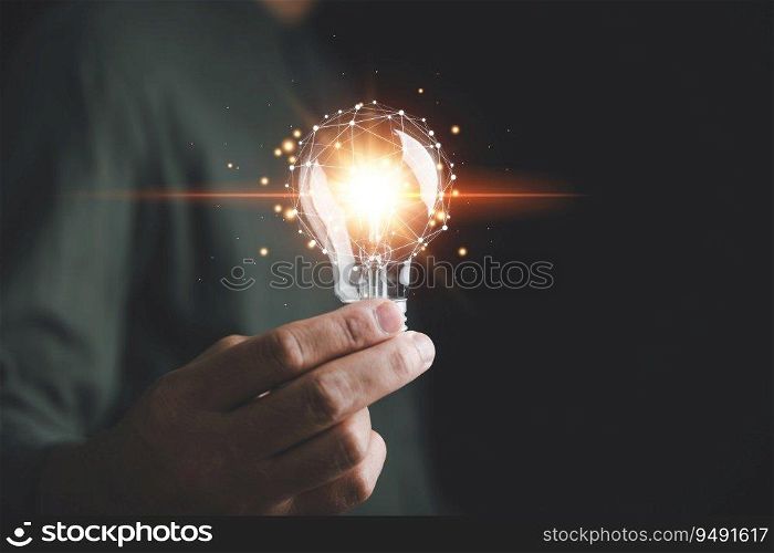 A man holds a bright light bulb, symbolizing creative new ideas, innovation, and inspiration. The concept of solution-oriented thinking and innovative technology is showcased in this creative moment.