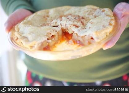 A man holds a homemade apple pie sprinkled with cinnamon.