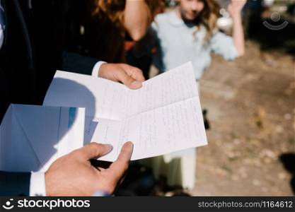 A man holds and reads a piece of paper in his hands close-up. Man holds in his hands a piece of paper close-up