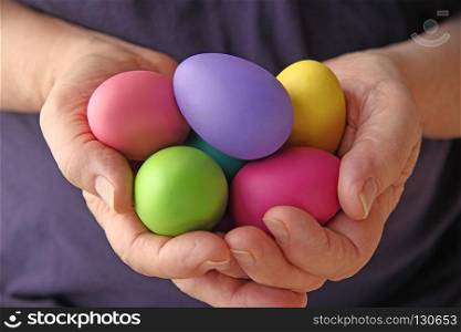 A man holds several brightly colored Easter eggs