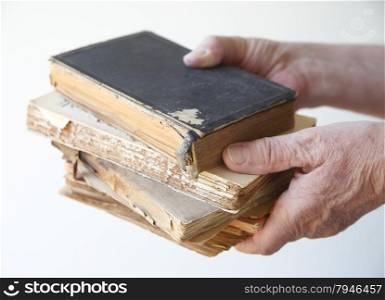 A man holds several old, damaged books.