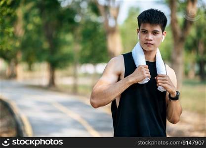 A man in a black shirt stood and held a handkerchief over his neck to wipe his face after exercising.