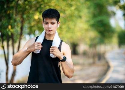 A man in a black shirt stood and held a handkerchief over his neck to wipe his face after exercising.