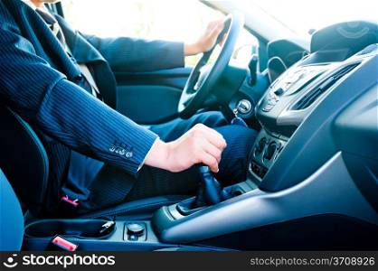 a man in a business suit in the car changes gear