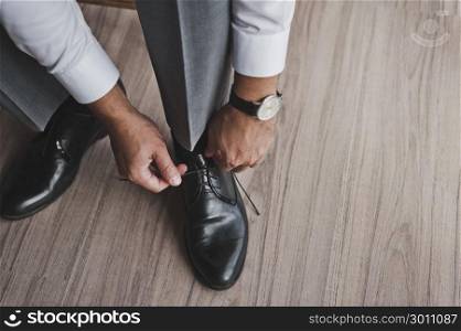 A man in a business suit ties his shoelaces.. The process of tying your shoes to mens Shoe 334.