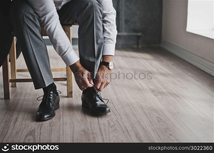 A man in a business suit ties his shoelaces.. The process of tying your shoes to mens Shoe 145.