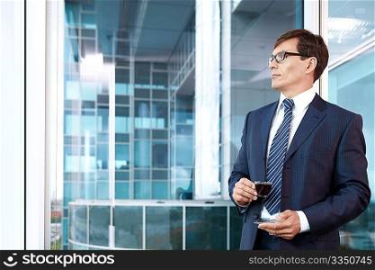 A man in a business suit with a cup of coffee