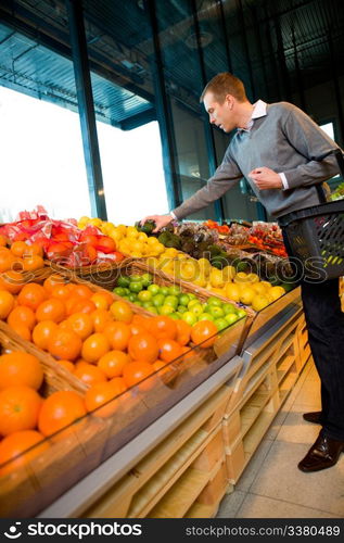 A man in a grocery store buying fruits and vegetables