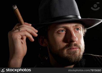A man in a hat with a cigar close-up