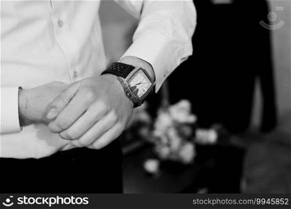 A man in a shirt looks at a wristwatch.. man in a shirt looks at a wristwatch.