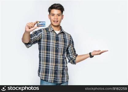 A man in a striped shirt opens his left hand and holds a credit card.