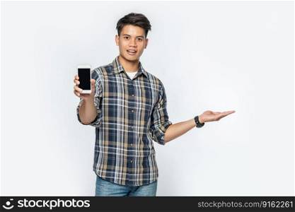 A man in a striped shirt opens his left hand and holds a smartphone.