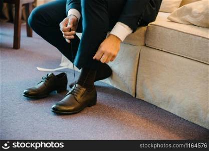 A man in a suit puts shoes. A man in a suit puts shoes on his feet.