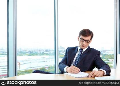 A man in business suit signs documents in the office