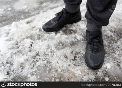 A man in winter waterproof sneakers stands on an icy road, shoes for winter walks. Walks in the open air. A man in winter waterproof sneakers stands on an icy road, shoes for winter walks. Walks in the open air.